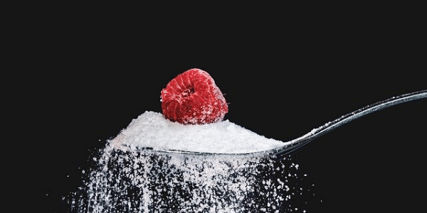 Framboise dans une cuillère remplie de sucre blanc