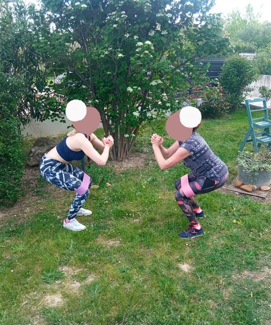 Squats avec élastiques en duo dans le jardin