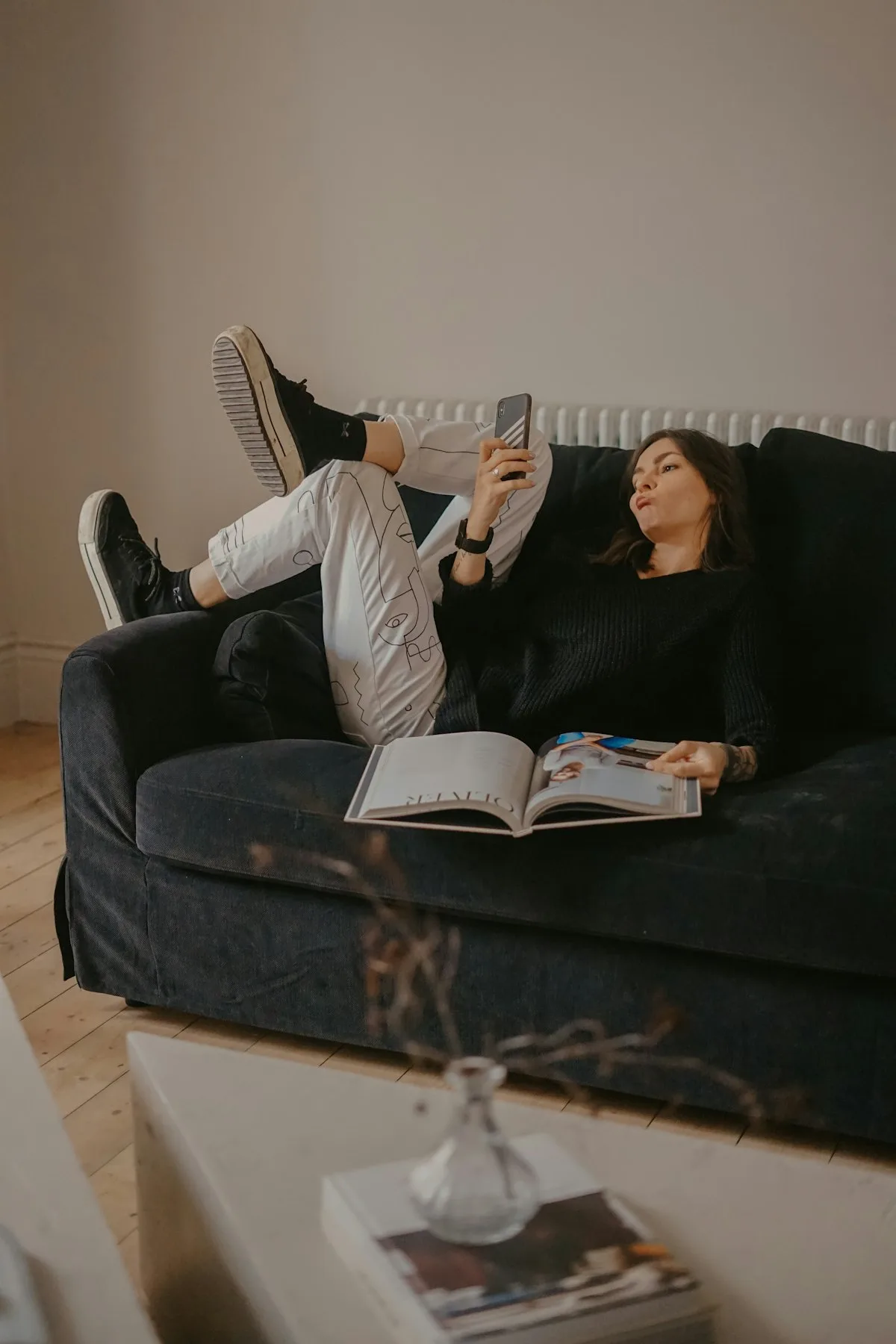 Femme allongée sur son canapé, téléphone à la main